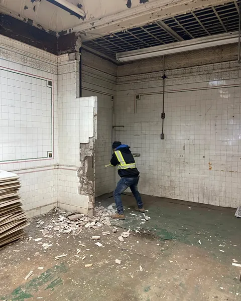 Crew member demolishing a tiled wall