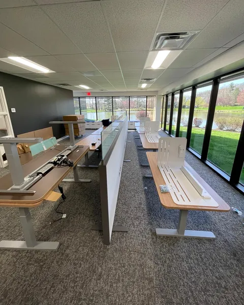 Height-adjustable desks being installed by a lakeside window wall